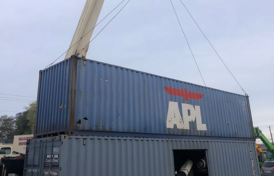 Crane lifting a blue APL intermodal shipping container during a Campbell Logistics coordination job